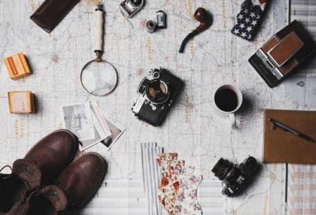 Budget Travel Experience - camera, pair of brown shoes, white ceramic mug, grey and black pen, brown smoking pipe