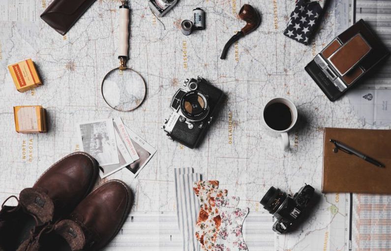 Budget Travel Experience - camera, pair of brown shoes, white ceramic mug, grey and black pen, brown smoking pipe