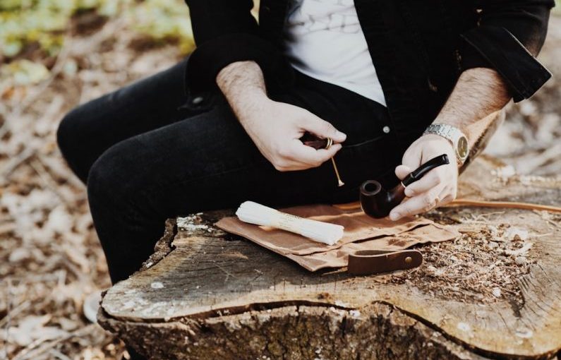 Bespoke Travel - man holding tobacco while sitting on wood slab