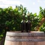 Wine Tour - two black glass bottles on the top of the brown wooden barrel