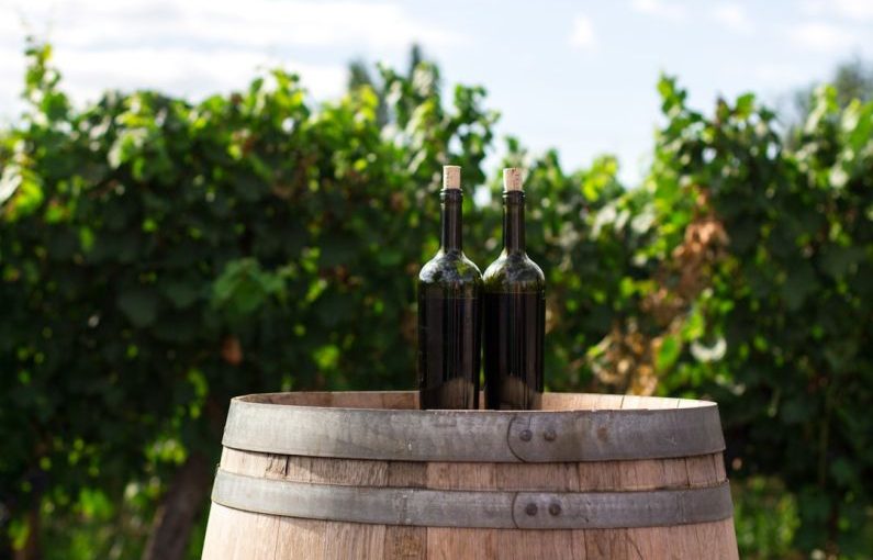 Wine Tour - two black glass bottles on the top of the brown wooden barrel