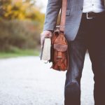 Carry-on Luggage - man holding book on road during daytime