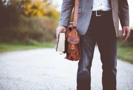 Carry-on Luggage - man holding book on road during daytime