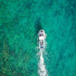 Travel Drone - aerial photo of white boat sailing on body of water at daytime