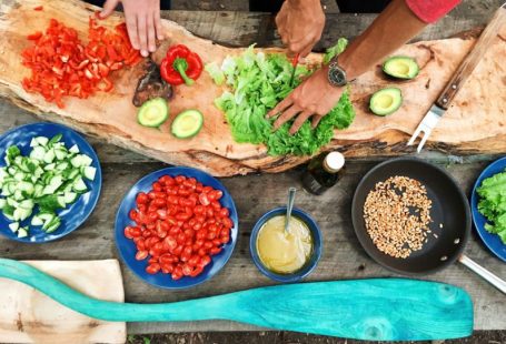 Cooking Classes - person slicing green vegetable in front of round ceramic plates with assorted sliced vegetables during daytime