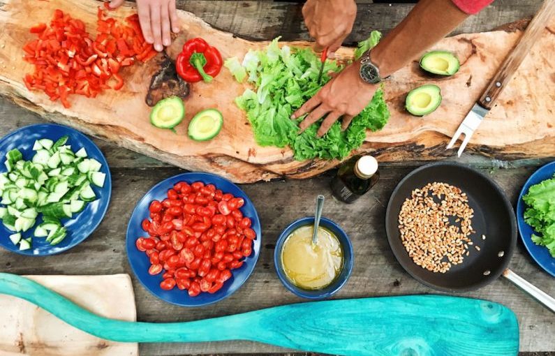 Cooking Classes - person slicing green vegetable in front of round ceramic plates with assorted sliced vegetables during daytime