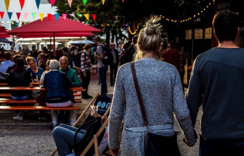 Food Festival - man and woman walking while holding hands during daytime