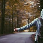 Solo Traveler - person standing beside road doing handsign