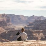 Pet Travel - person with dog sitting on Grand Canyon cliff