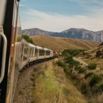 Eco Travel - white train with the distance of mountain during daytime