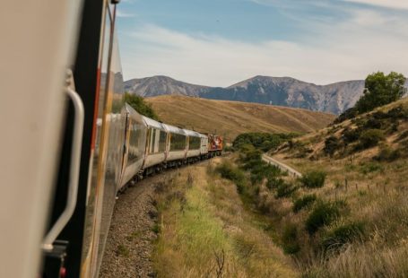 Eco Travel - white train with the distance of mountain during daytime