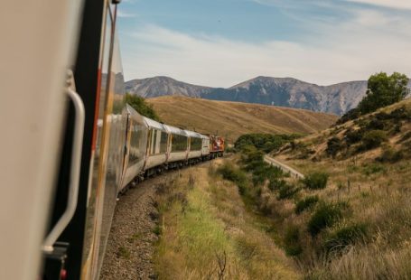 Eco Travel - white train with the distance of mountain during daytime
