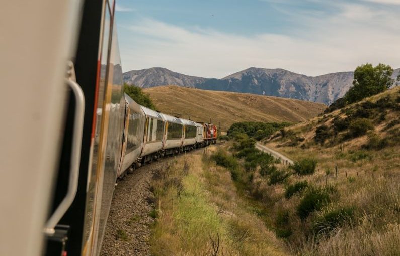 Eco Travel - white train with the distance of mountain during daytime