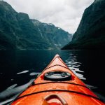 Kayaking Fjords - orange canoe on lake surrounding with mountain at daytime