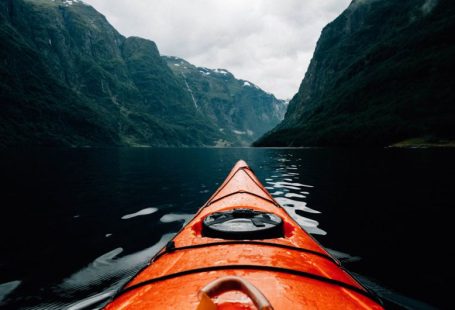 Kayaking Fjords - orange canoe on lake surrounding with mountain at daytime