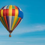 Hot Air Balloon - panning photography of flying blue, yellow, and red hot air balloon