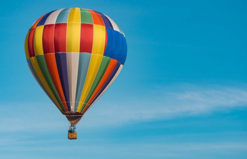 Hot Air Balloon - panning photography of flying blue, yellow, and red hot air balloon