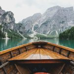 Planning Travel - brown wooden boat moving towards the mountain