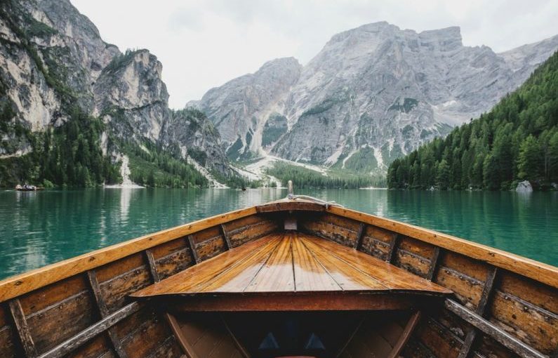 Planning Travel - brown wooden boat moving towards the mountain