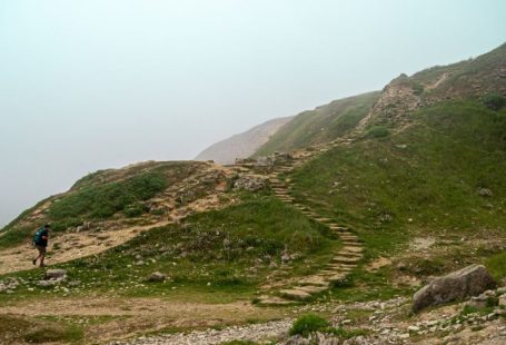 Solo Journey - a person walking up a hill with a backpack