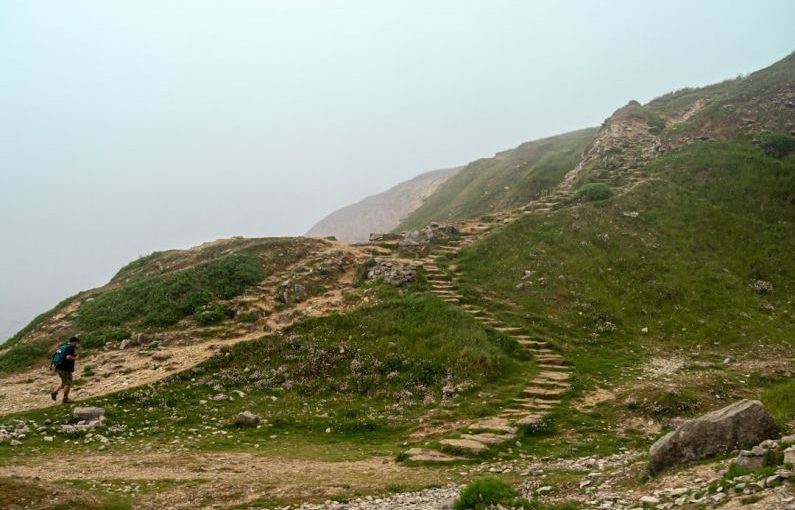 Solo Journey - a person walking up a hill with a backpack