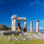 Ancient Ruins - gray concrete pillar on green grass field under blue sky during daytime