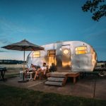 Eco Travel Gear - man and woman sitting in front of RV trailer