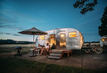 Eco Travel Gear - man and woman sitting in front of RV trailer