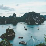 Eco Tour - high-angle photography of boats on water near hill during daytime